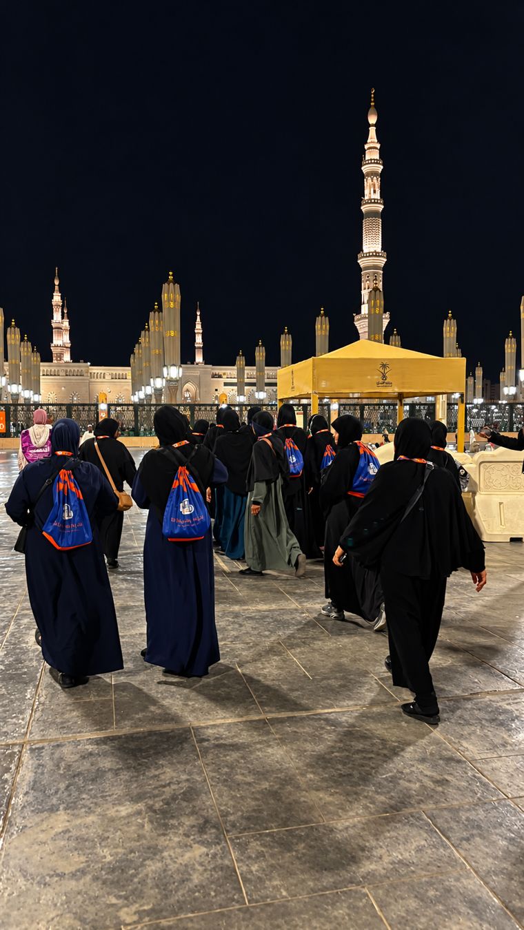 Taif pilgrims walking together towards Masjid an-Nabawi at night, each carrying the Taif bag